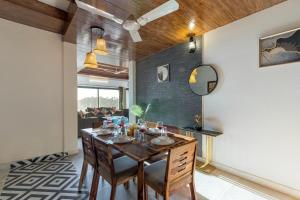 une salle à manger avec une table et des chaises en bois dans l'établissement Alaya Stays Evara - 2 BHK Hilltop Hideaway With Balcony, Fireplace & Scenic Views, à Mussoorie