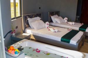 two beds in a room with a bath tub at Amboseli Amanya Lodge in Rift Valley
