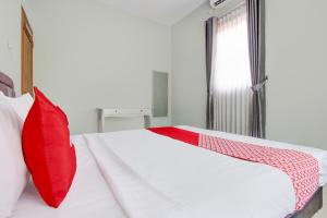 a bedroom with a red pillow on a bed at Hotel O D'draman Homestay Syariah in Wanujoyo +26 photos