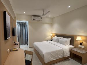 a bedroom with a bed and a desk and a tv at Mastiff Hotel Hinjawadi Pune in Pune