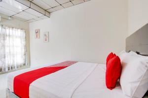 a bedroom with a large white bed with red pillows at Hotel O Homestay Ayana Syariah in Yogyakarta +27 photos