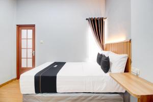 a bedroom with a large bed and a wooden table at Capital O 94314 Sunny Co Living in Yogyakarta