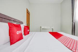 a bedroom with a white bed with red pillows at Hotel O D'draman Homestay Syariah in Wanujoyo