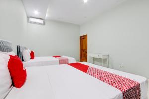 two beds in a white room with red and white sheets at Hotel O D'draman Homestay Syariah in Wanujoyo