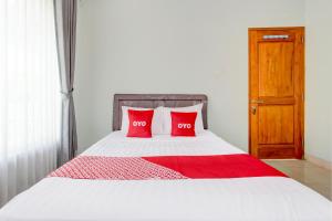a bed with two red pillows on top of it at Hotel O D'draman Homestay Syariah in Wanujoyo