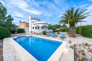 a pool in front of a house with a palm tree at Villa Flor in Les tres Cales