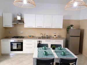 a kitchen with white cabinets and a table with chairs at Station House in Formia