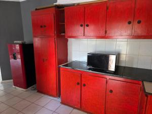 a kitchen with red cabinets and a black microwave at EzekMary Res in Polokwane