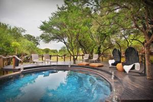 a swimming pool with chairs and a table and trees at Itaga Luxury Private Game Lodge in Bela-Bela