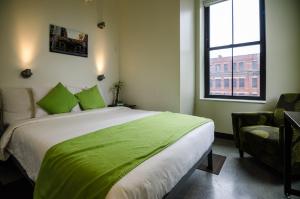Un dormitorio con una cama con sábanas verdes y una ventana en HI Boston Hostel, en Boston