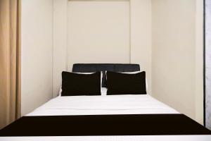 a bed with black and white sheets and pillows at Collection O Near UNRIKA Formerly Dory Inn in Sekupang +26 photos