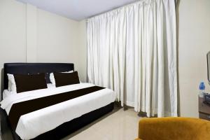 a bedroom with a bed and a window with white curtains at Collection O Near UNRIKA Formerly Dory Inn in Sekupang