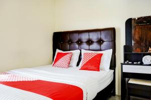 a bedroom with a bed with red and white pillows at Hotel O Mantari Guesthouse in Bukittinggi
