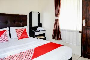 a bedroom with a bed with red and white pillows at Hotel O Mantari Guesthouse in Bukittinggi