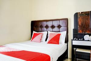 a bedroom with a bed with red and white pillows at Hotel O Mantari Guesthouse in Bukittinggi +29 photos