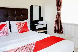 a bedroom with a bed with red and white pillows at Hotel O Mantari Guesthouse in Bukittinggi