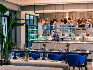 アムステルダムにあるINK Hotel Amsterdam - MGallery Collectionのテーブルと椅子のあるレストラン、キッチンが備わります。