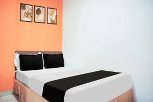 a bedroom with a white bed with three pictures on the wall at Collection O Bukit Kecil Near Palembang Indah Mall Formerly Hostel 77 in Palembang