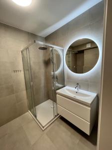 a bathroom with a shower and a sink and a mirror at Apartament Julia 1-4 os Starowapiennikowa 42a z balkonem, klimatyzacją i miejscem parkingowym in Kielce +17 photos
