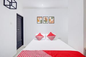 a bedroom with a white bed with red pillows at Collection O Gunung Sahari Near Ancol in Jakarta