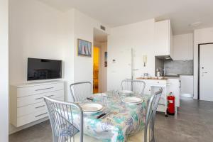 a dining room with a table and chairs and a kitchen at La Terrazza sul Mare with parking in Lignano Sabbiadoro +19 photos