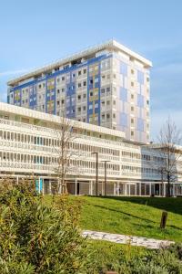 a large white building with a field in front of it at La Terrazza sul Mare with parking in Lignano Sabbiadoro