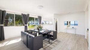 une salle à manger avec une table, des chaises et des fenêtres dans l'établissement Waterfront Cottage, à New South Wales 