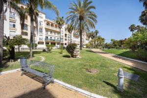 park z ławką przed budynkiem w obiekcie Apartamento Los Jardines w mieście El Puerto de Santa María