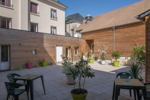un patio con mesas y sillas y un edificio de ladrillo en Logis de la Barque en Beaumont-sur-Sarthe