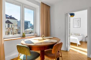 a dining room with a table and chairs and a window at Wola Ratusz Serene Apartment by BookingHost in Warsaw