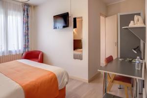 a hotel room with a bed and a desk and a tv at Logis de la Barque in Beaumont-sur-Sarthe