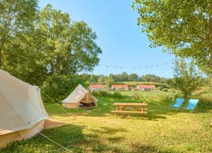 a tent and a picnic table and chairs in a field at Camping de Salviac in Salviac