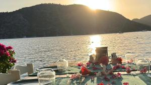 a table with wine glasses and flowers on the water at Selimiye Çapkını in Marmaris