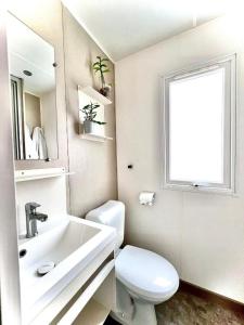 a white bathroom with a toilet and a sink at Camping Village Tuscia Tirrenica in Tarquinia