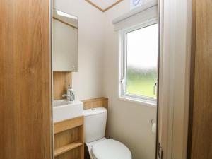 a bathroom with a toilet and a sink and a window at 75 Foxburrow Hang in Great Yarmouth