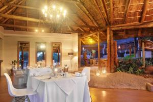 un comedor con mesas blancas y una lámpara de araña en Itaga Luxury Private Game Lodge, en Bela-Bela