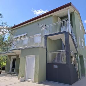 un immeuble vert avec un balcon dans l'établissement Apartments Oliva - Maslina, à Bilice
