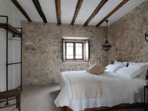 a bedroom with a large bed and a stone wall at Casa do Cruzeiro in Ourém