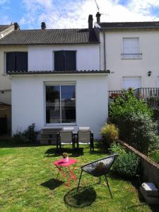 een tuin met twee stoelen en een tafel en een huis bij Maison proche centre ville et circuit avec jardin in Le Mans