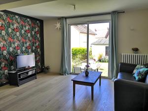 een woonkamer met een bank, een tv en een tafel bij Maison proche centre ville et circuit avec jardin in Le Mans