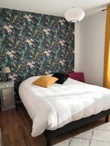 een slaapkamer met een bed met een bloemenbehang bij Maison proche centre ville et circuit avec jardin in Le Mans