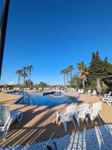 勒格罗-迪鲁瓦Mobil-home Camping -La Marine - 4 Étoiles - Grau du Roi - B038的一组坐在游泳池前的白色椅子 更多37张照片