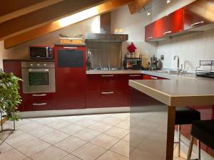 a large kitchen with red cabinets and a counter at La Mansardina in Palmanova