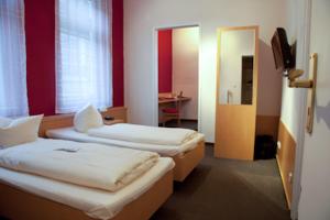 two beds in a room with red walls and a door at Hotel Zur Linde in Meldorf