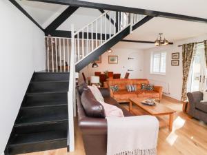 a living room with a couch and a staircase at Old Stable Cottage in Alnmouth