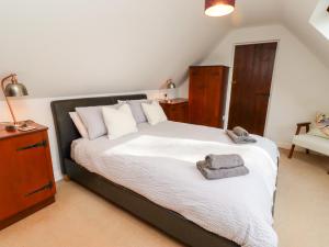 a bedroom with a large bed with white sheets and pillows at Old Stable Cottage in Alnmouth