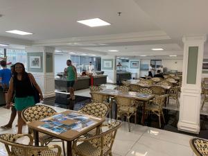 a woman standing in a restaurant with tables and chairs at Hotel Piazza diRoma com acesso ao Acqua Park e Splash in Caldas Novas