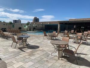 a patio with tables and chairs next to a pool at Hotel Piazza diRoma com acesso ao Acqua Park e Splash in Caldas Novas