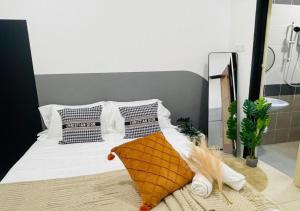 une chambre avec un lit avec des draps blancs et des oreillers dans l'établissement Tambun Guesthouse 14pax nearby Sunway by IWH Suites, à Ipoh