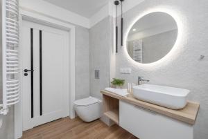 a white bathroom with a sink and a mirror at Apartament Relax Rogowo Balkon & Parking by Noclegi Renters in Rogowo